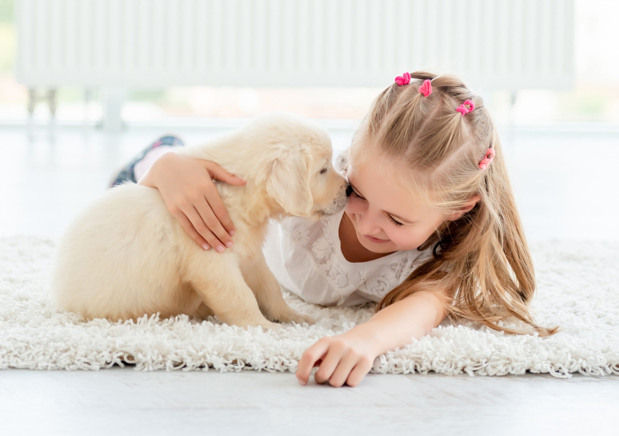 Puppy and little girl playing on carpet